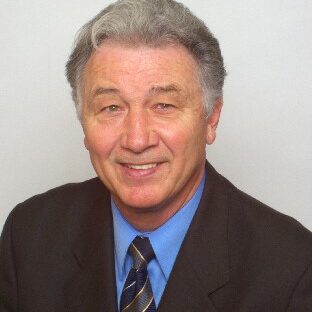 A man in suit and tie smiling for the camera.